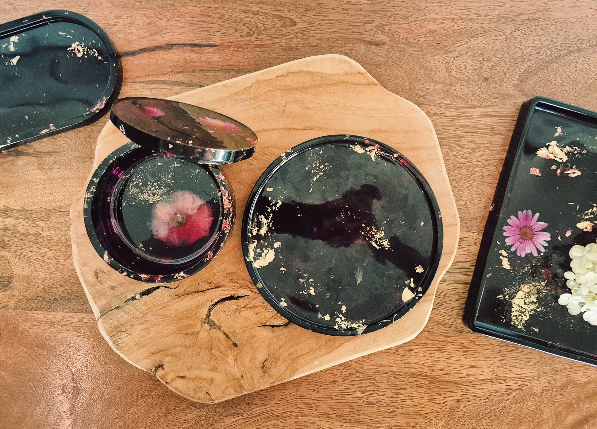 Set aus Epoxidharz-Schalen mit violett-goldenem Farbspiel, arrangiert auf Holzbrett – Maliora Designs