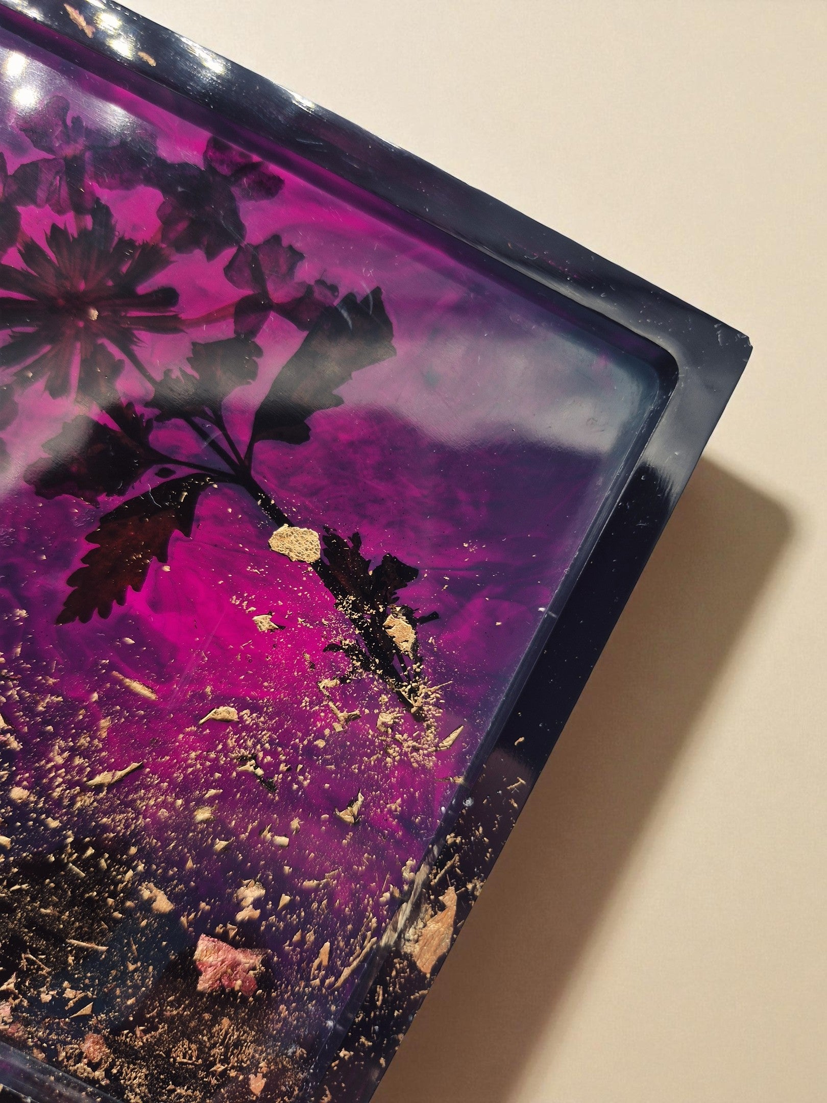 Nahaufnahme der glänzenden Oberfläche eines violett-goldenen Epoxidharz-Tabletts mit Blüten – Maliora Designs