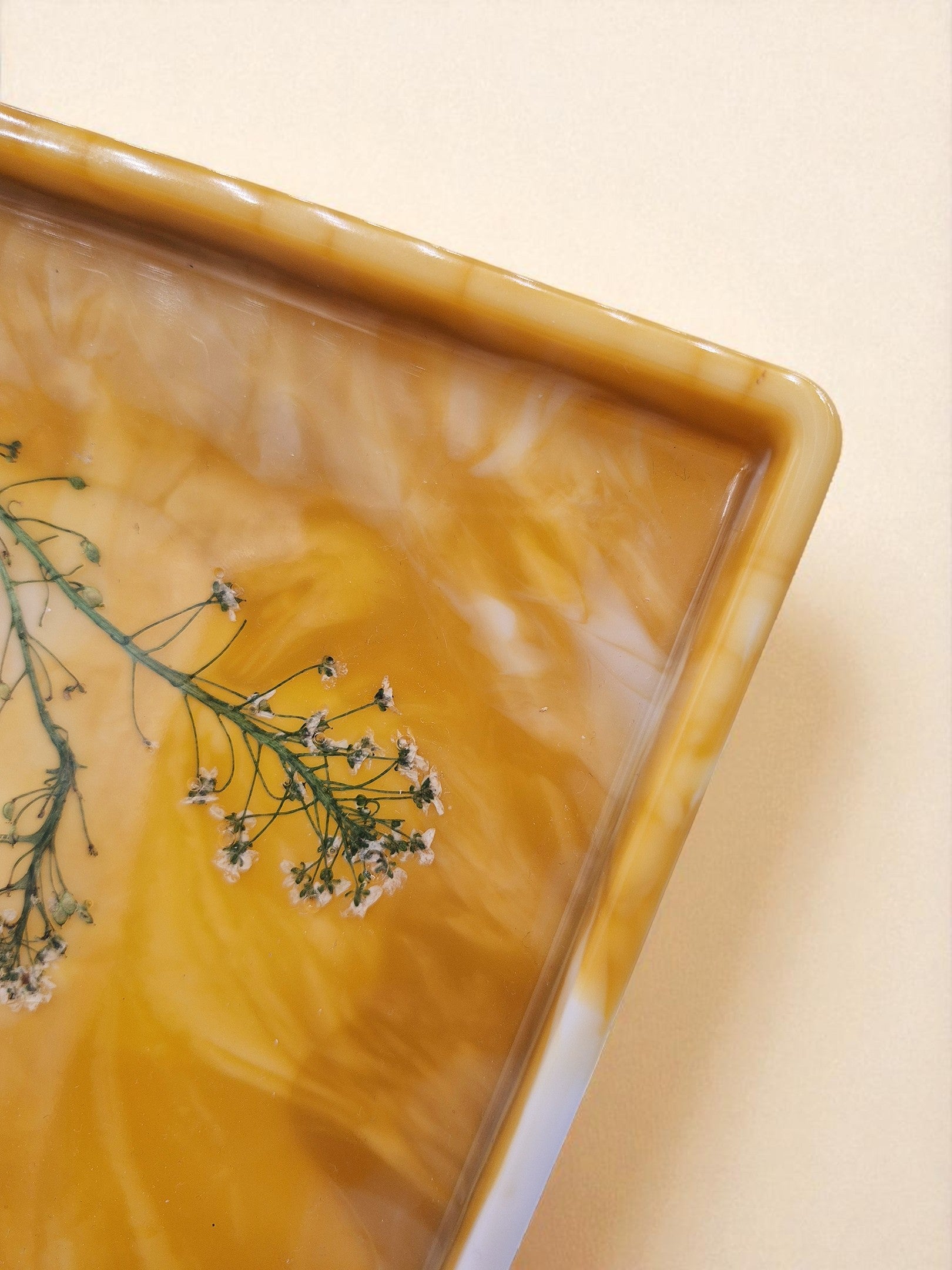 Detailaufnahme des goldgelben Epoxidharz-Tabletts mit eingegossenen Blüten und Blattgold – Kollektion Golden Dawn