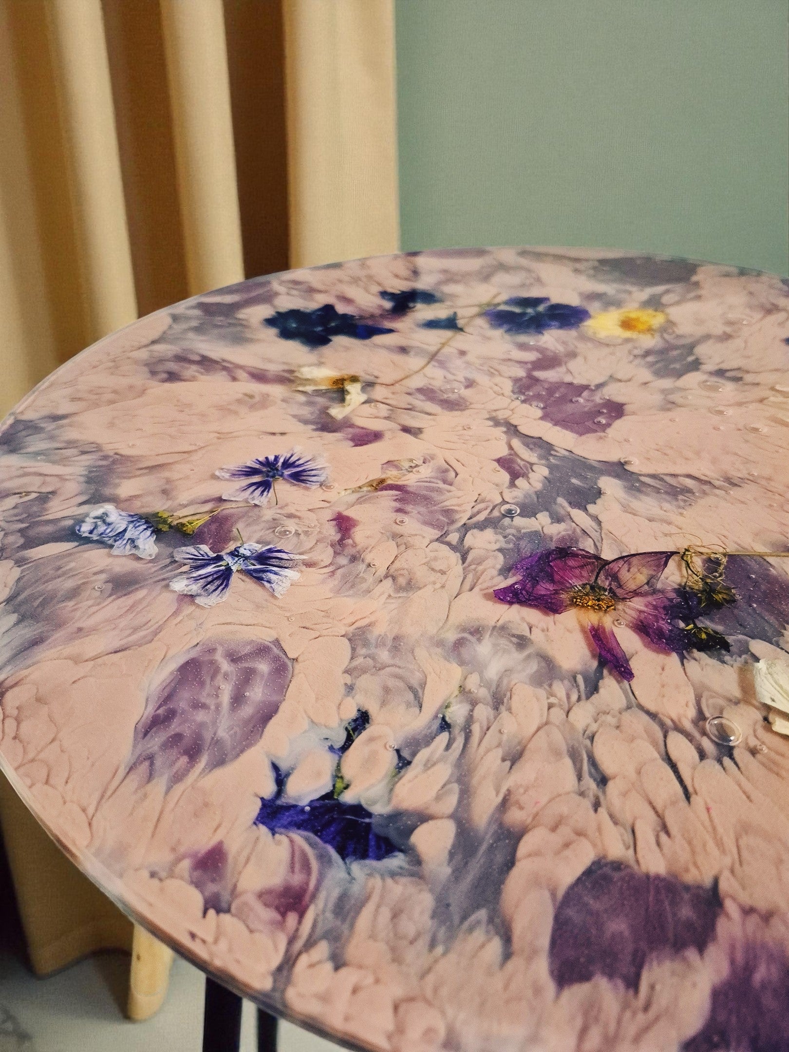 Beistelltisch „Violet Veil“ mit sanfter Beleuchtung vor beigem Vorhang – Fokus auf die kunstvolle Blütenstruktur und fließende Farbverläufe.