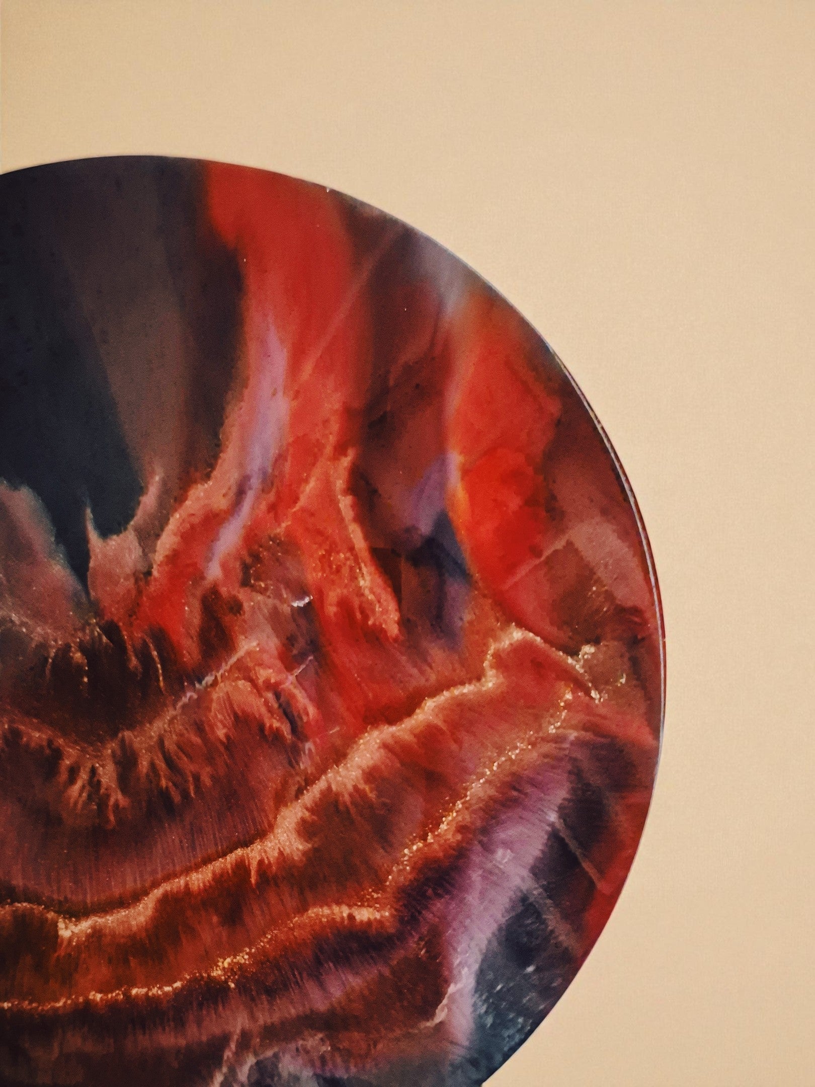 Runder Epoxidharz-Tisch ‚Falling Ember‘ mit schwarzen Beinen und goldenen Endkappen, inszeniert vor beigem Stoffhintergrund mit Licht- und Schattenspiel.