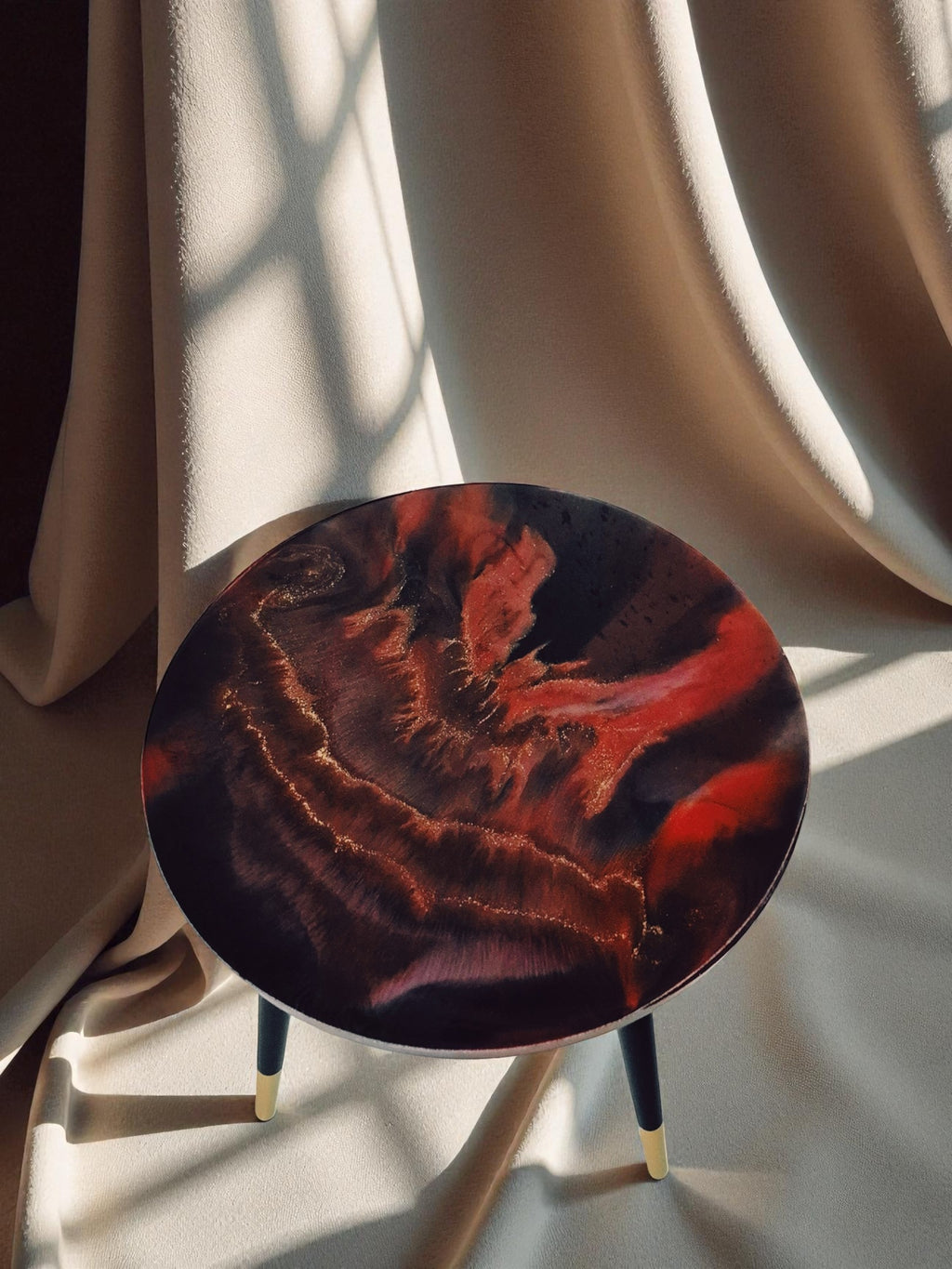 Beistelltisch ‚Falling Ember‘ von oben fotografiert, rot-schwarzer Epoxidharz-Tisch mit glühender Struktur und goldenen Linien auf beigem Hintergrund.