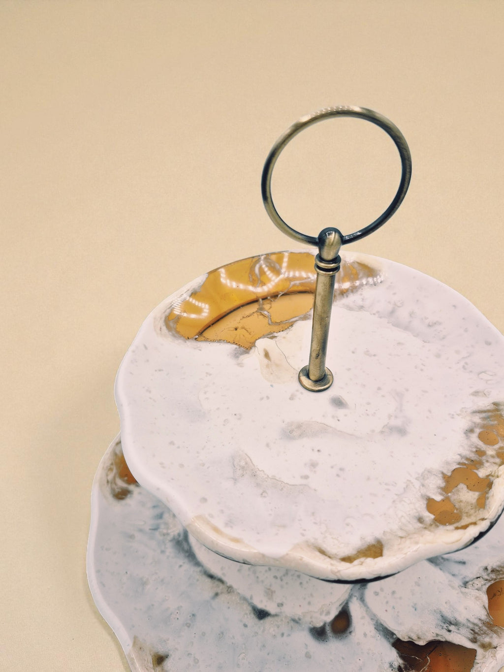 Detailansicht der Etagere „Melted Sun“ mit goldfarbenem Mittelstab und glänzender Oberfläche, die an geschmolzenes Licht erinnert.