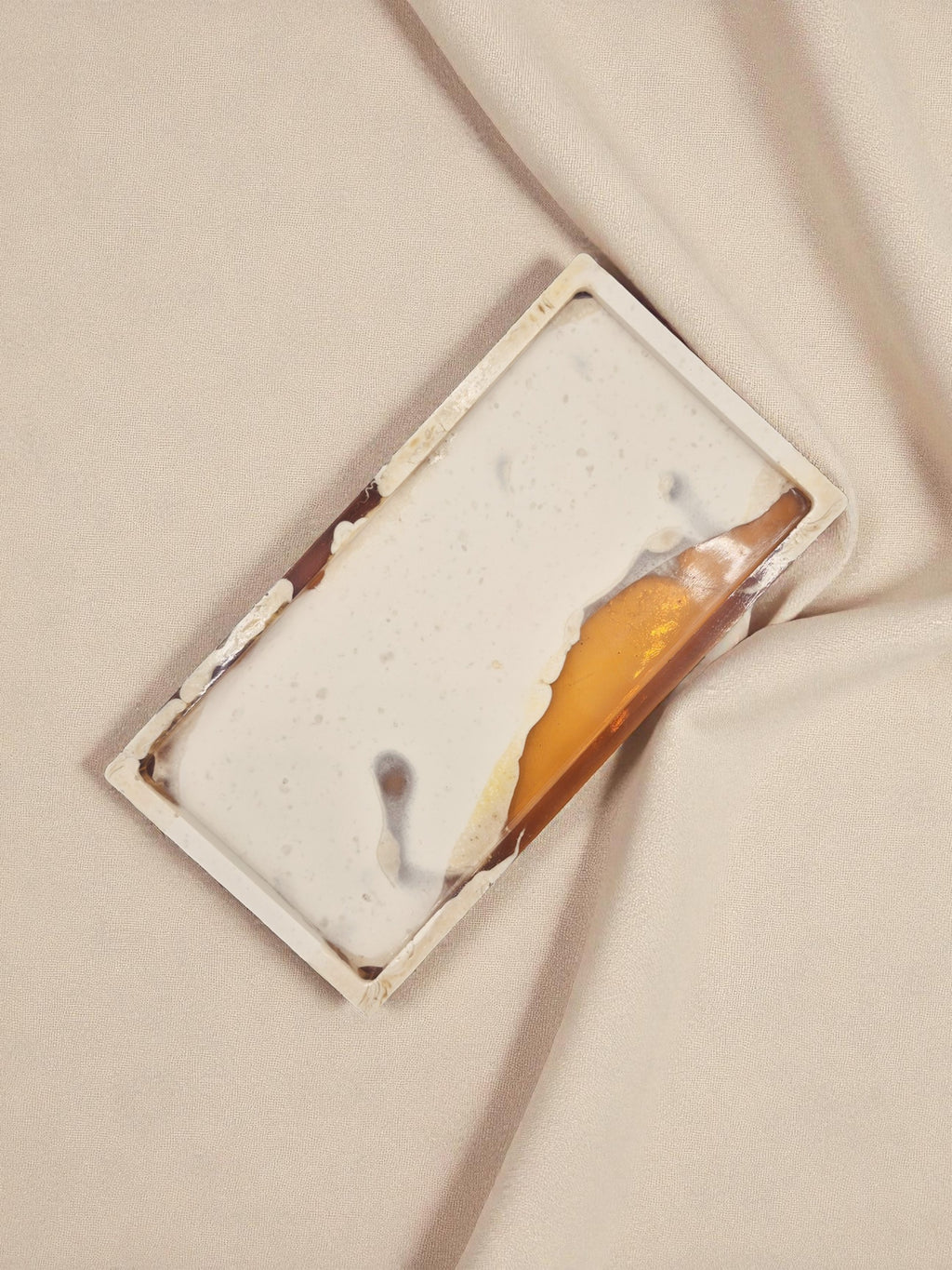 Rechteckiges Tablett „Melted Sun“ aus Jesmonite und Epoxidharz in Creme und Gold, Nahaufnahme mit sanftem Lichteinfall auf hellem Hintergrund.