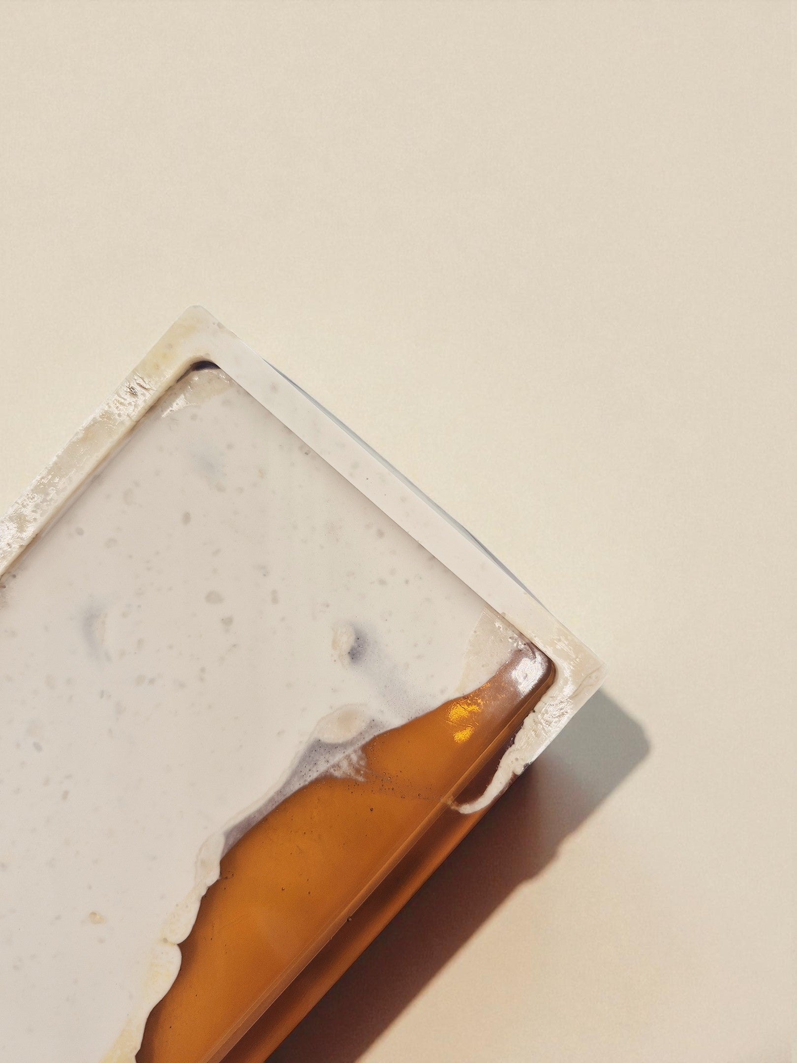 Rechteckiges Tablett „Melted Sun“ aus Harz und Jesmonite mit warmem Farbverlauf, in Seitenansicht vor beigem Hintergrund arrangiert.