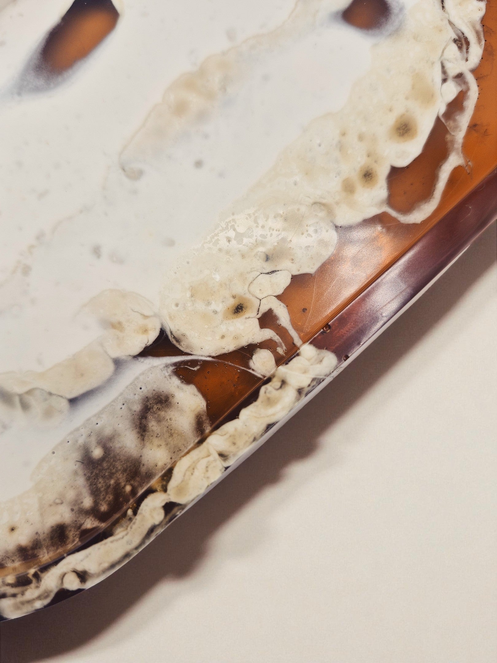 Detailaufnahme der glänzenden Oberfläche des Tabletts „Melted Sun“ mit goldtransparenter Harzstruktur.